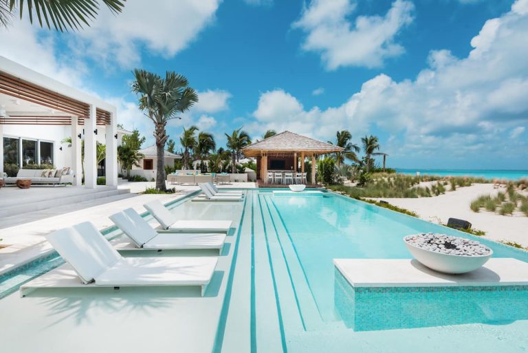 A long pool with loungers and palms at a beachfront villa in Turks and Caicos