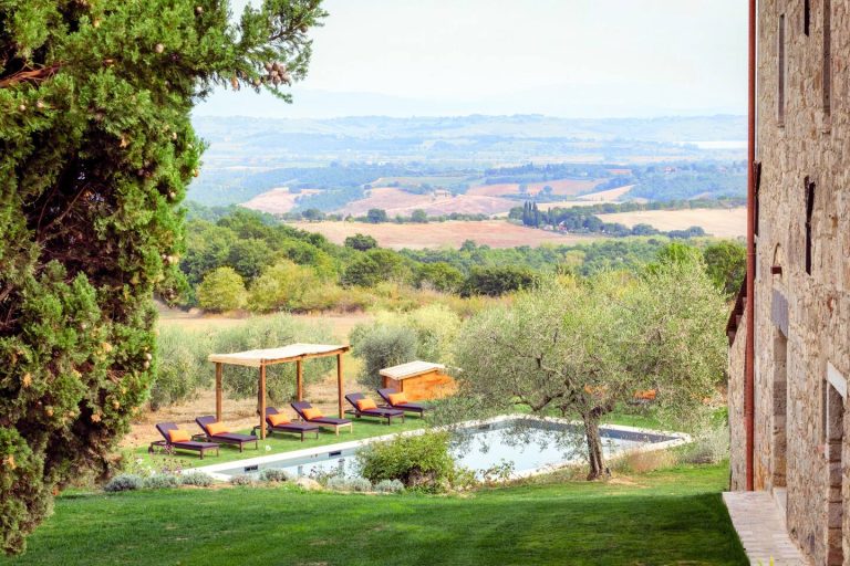 A pool terrace among olive trees above the Tuscan hills