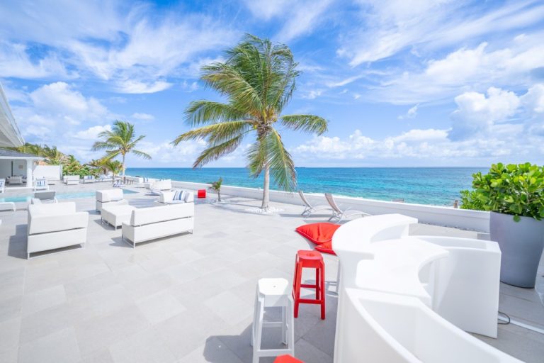 A white roof terrace with loungers above the sea at a villa in St Martin