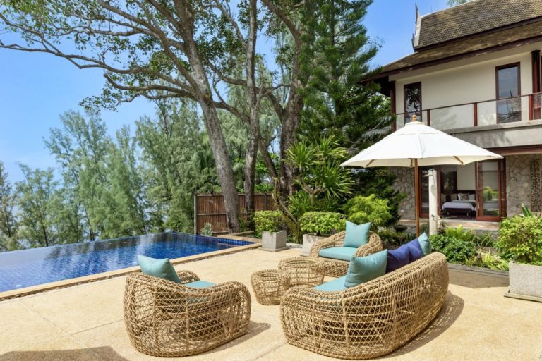A pool terrace with an umbrella and armchairs at a villa in Thailand