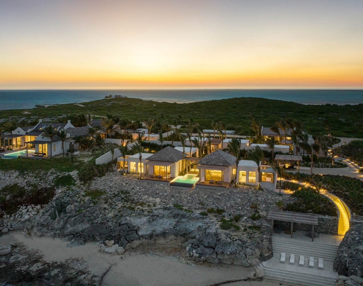 The villas and bungalows of Dream Estate lit at sunset above the sea on Ambergris Cay, Turks and Caicos