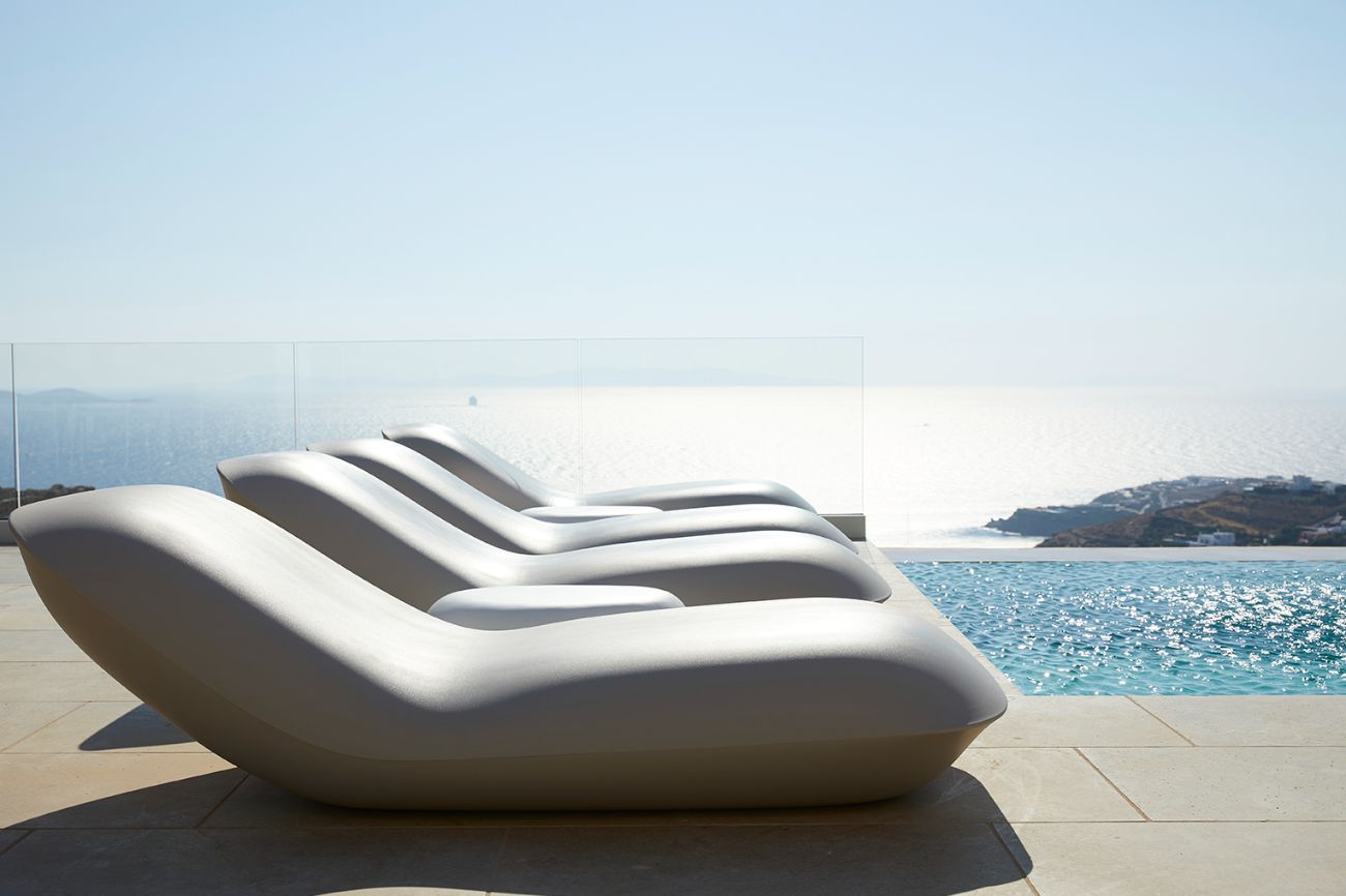 10 Best Places to Travel in June for a Luxury Getaway 4 a row of lounge chairs by a pool in Mykonos