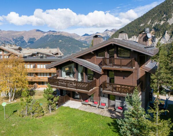 A large timber chalet below snow-capped peaks
