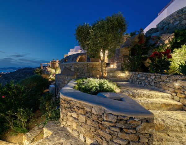 The Luxury Traveler’s Guide on How to Get to Mykonos from USA 2 Stone steps through the garden of Villa Zeus at dusk, with the sea beyond