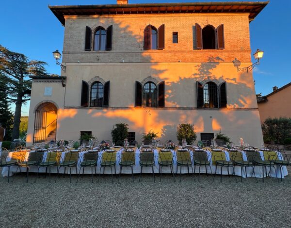 Long tables laid for dinner in front of Villa Elsa at dusk