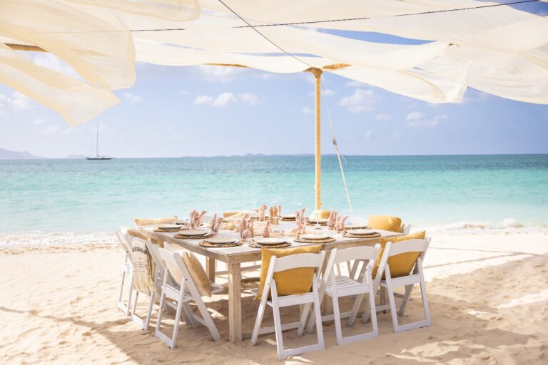 A lunch table set on the sand under white shade sails, Anguilla