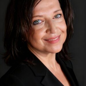 Woman in black blazer, dark background. Piccinin Sabrina CEO Haute Retreats