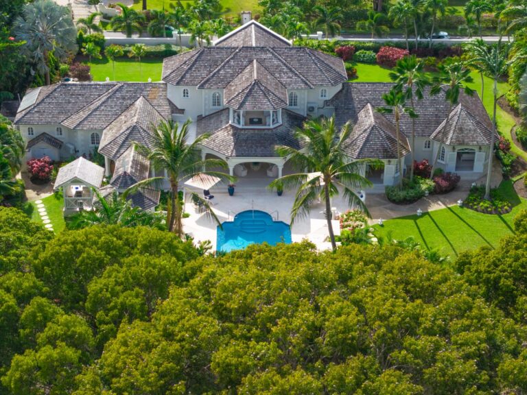 A Barbados villa from above: grey shingle roofs, a colonnaded pool terrace and gardens framed by trees