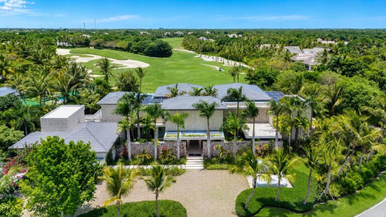 A white villa among palms beside a golf course, from the air