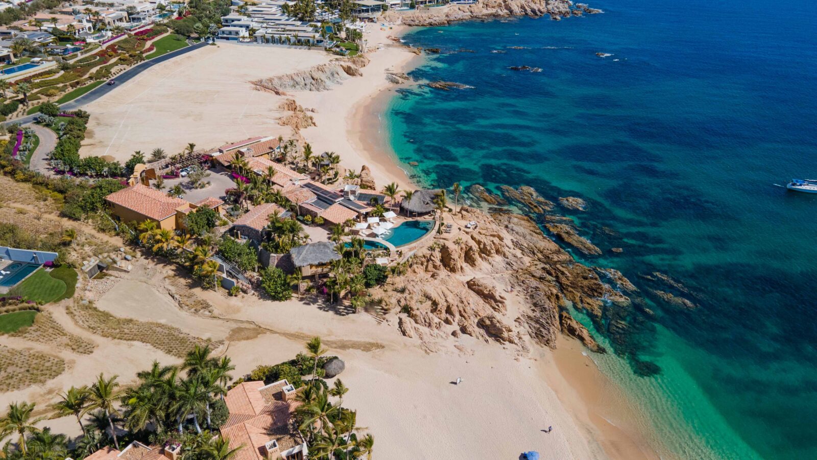 Aerial view of Chileno Bay, with Cielito del Mar among the palms on the rocks between two beaches