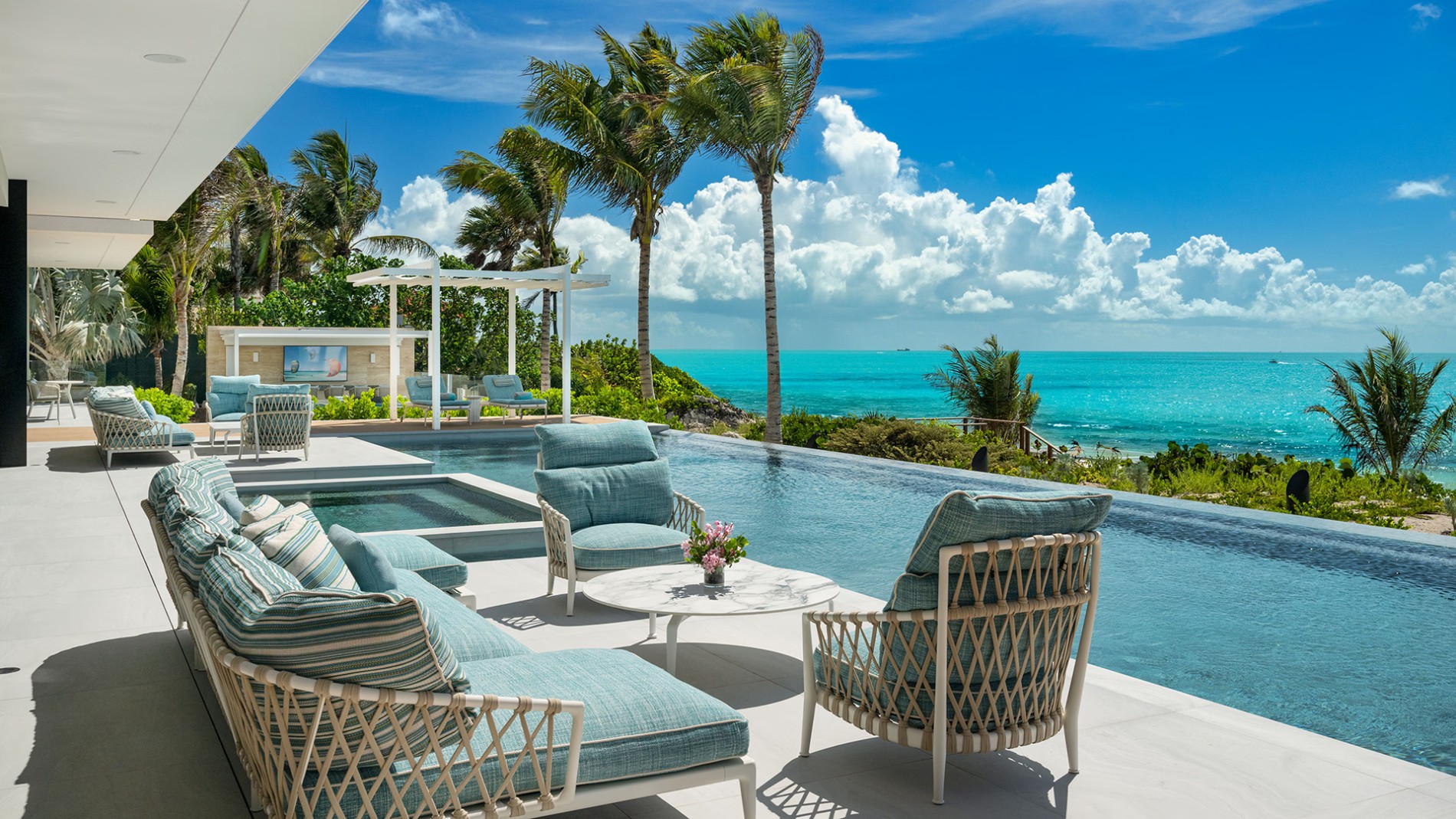 New Turks and Caicos Villa Rentals 1 Lounge chairs and the infinity pool of Villa Paradisa, with palms and the sea beyond