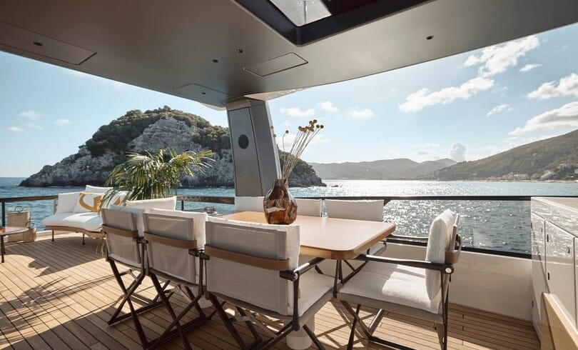 The teak aft deck laid for lunch under the flybridge, with a rocky island across the water