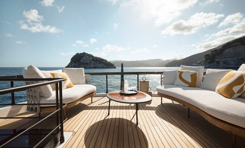 Sofas and a low table on the flybridge, open to the sea and the coast